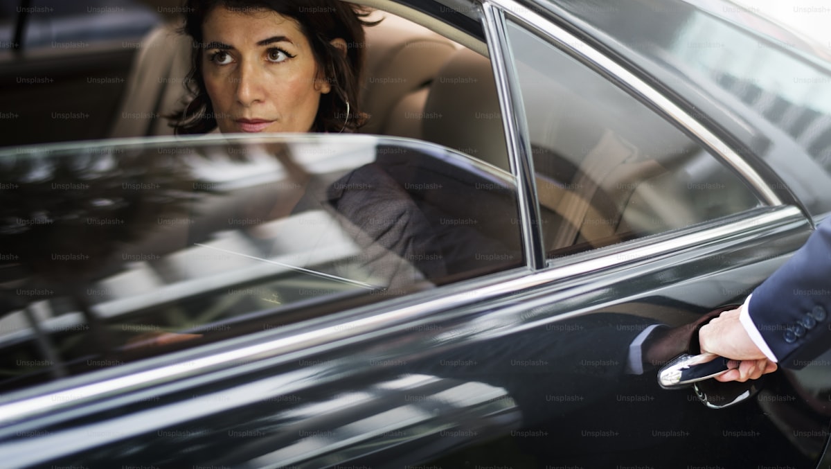 Suited chauffeur beside black luxury SUV